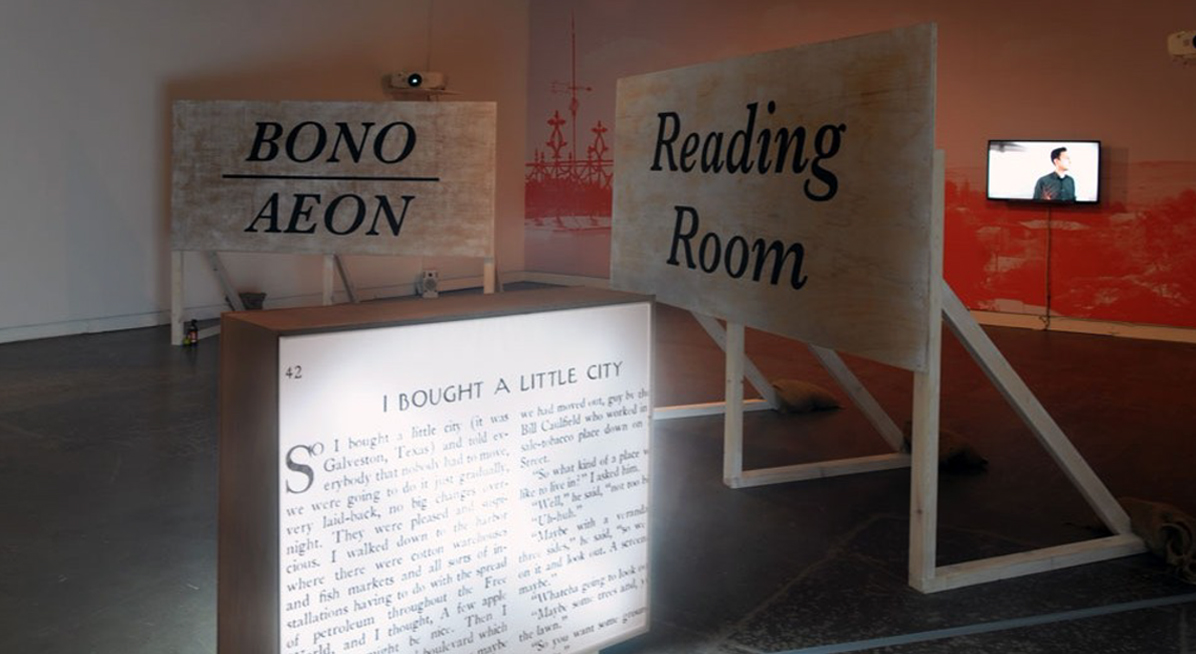 Art gallery installation with wooden billboard sculptures and lightbox with text
